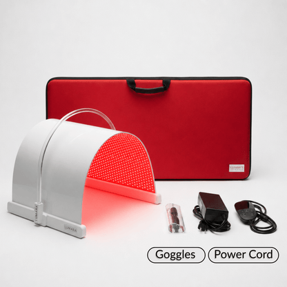 A red and white LED light therapy panel shown with its red carrying case, power adapter, cable, and a pair of black goggles on a light gray background. 